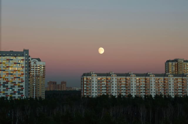 Captivating skyline of Balashikha, Russia, with full moon at dusk.