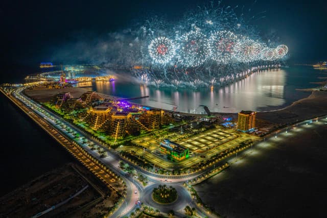 Dazzling fireworks illuminate Ras al Khaimah's harbor, captured in a stunning aerial night view.