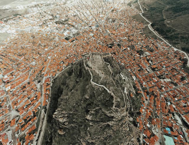 Drone shot capturing Afyonkarahisar Castle amidst the sprawling city with orange-roofed houses in Türkiye.