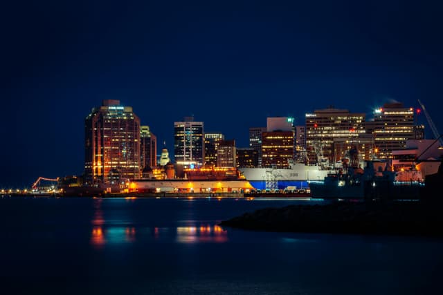 Illuminated Halifax skyline along the waterfront, featuring striking city lights reflected in the harbor at night.