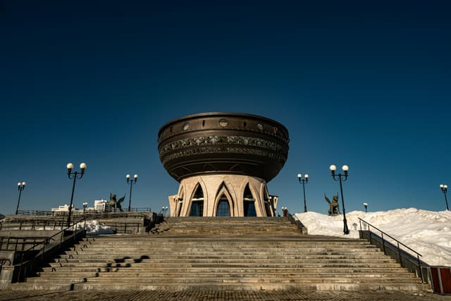 View of the Kazan Family Center monument with snowy stairs under a clear blue winter sky.