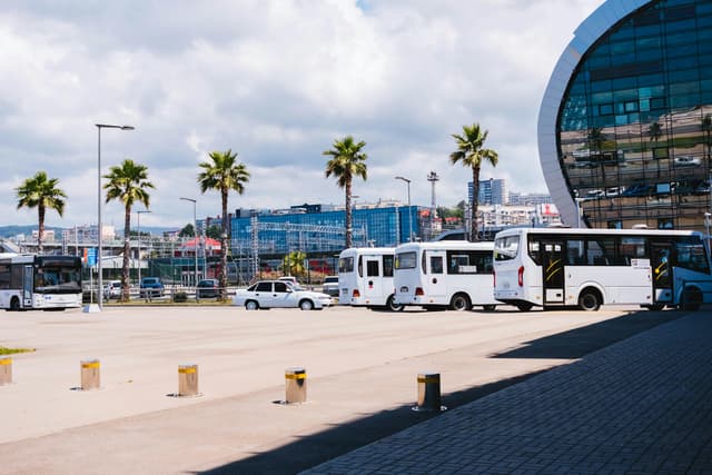 A modern urban view in Sochi, Russia featuring buses, palm trees, and contemporary architecture.
