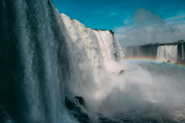 Majestic view of Iguazu Falls in Brazil showcasing a vibrant rainbow over cascading waters.
