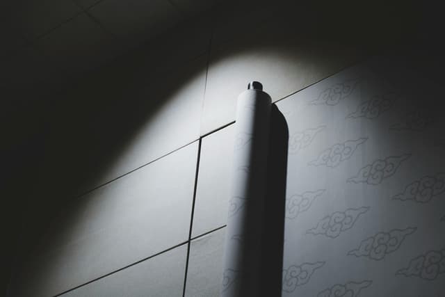 A rolled-up decorative scroll casting a shadow on a dimly lit wall.