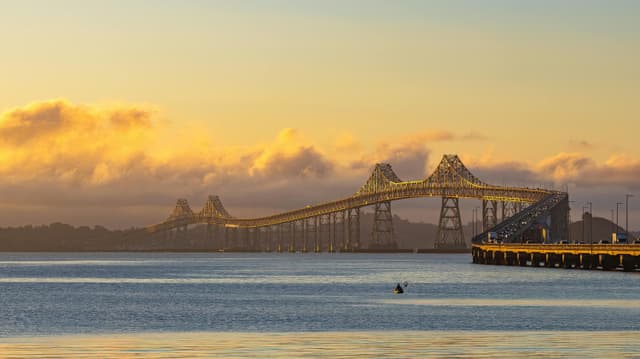 Serene view of Richmond-San Rafael Bridge during golden hour with calm ocean waters.