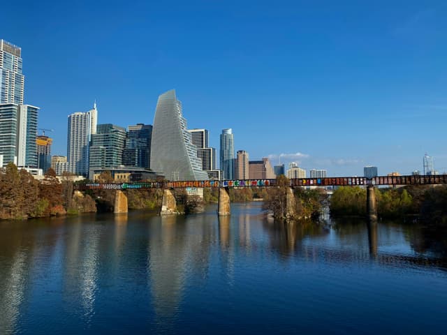 A stunning view of Austin's skyline with a bridge over the Colorado River under a clear blue sky.