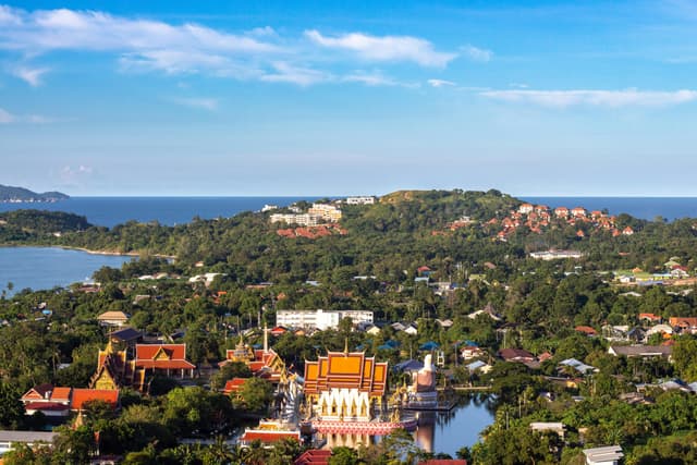 Aerial view of a coastal city featuring a bright temple and lush greenery.