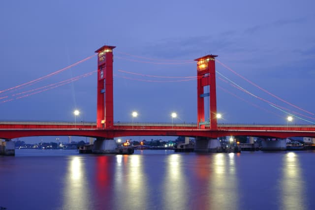 Stunning night view of Ampera Bridge in Palembang, Indonesia with beautifully reflected lights.