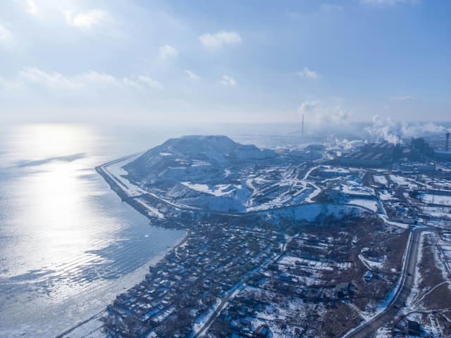 Aerial view of Mariupol, Ukraine in winter, showcasing coastline, residential districts, and steel mills.
