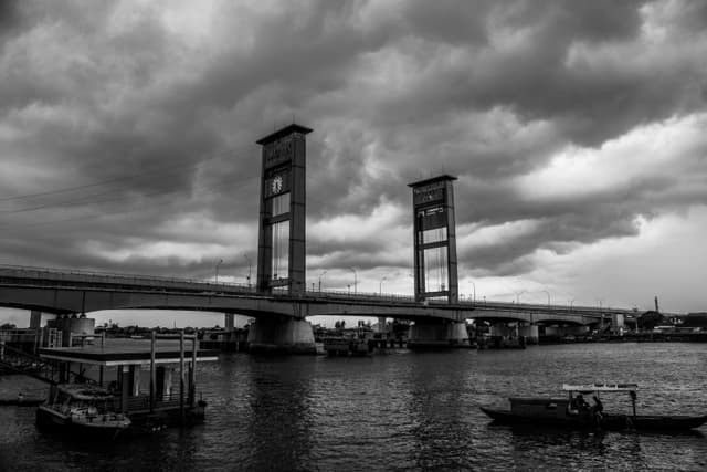 Dramatic black and white shot of Ampera Bridge over Musi River in Indonesia.