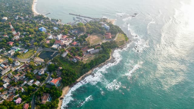 A stunning aerial shot of Tangalle's coastline showcasing lush greenery and vibrant ocean waves.