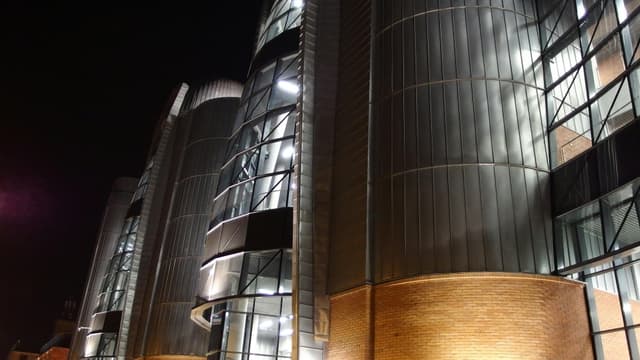 Night view of a contemporary building with steel and glass elements in Łódź, Poland.
