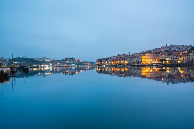 Stunning twilight reflection of Porto's cityscape on the Douro River.