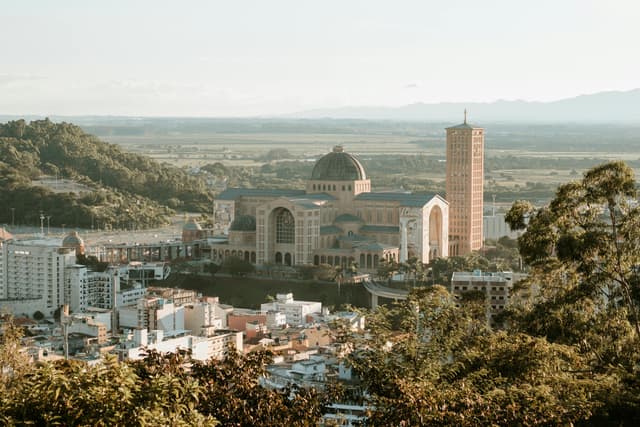 Scenic aerial view of Nossa Senhora Aparecida Basilica in Aparecida, Brazil, surrounded by lush landscape.