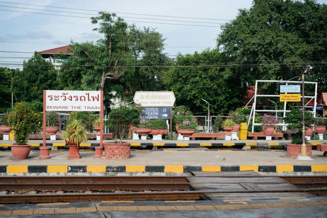 Ayutthaya train station platform featuring signage and greenery, highlighting Thai culture and travel.