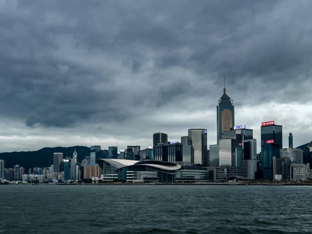Stunning view of Hong Kong Island skyline with modern skyscrapers under a dramatic overcast sky.