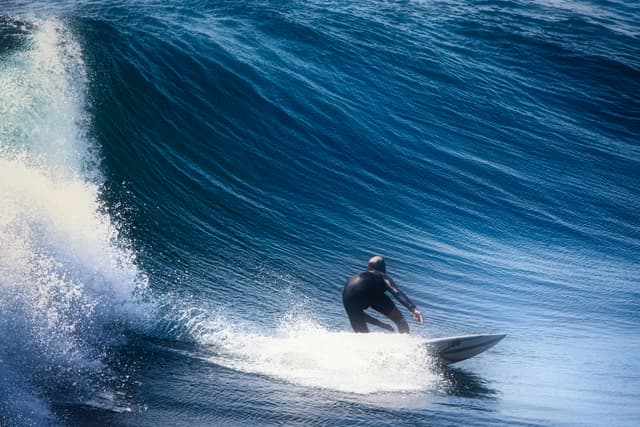 A surfer expertly navigates a large wave off the coast of Balikpapan, Indonesia.