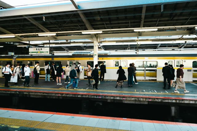 People on a busy train platform, ready to board a modern commuter train at a station.