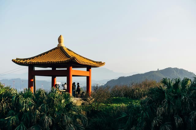 A serene pavilion in Keelung, Taiwan, with lush greenery and a beautiful cityscape in the background.