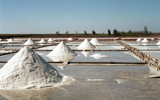 Scenic view of traditional salt fields with salt mounds under a clear sky in Tainan, Taiwan.