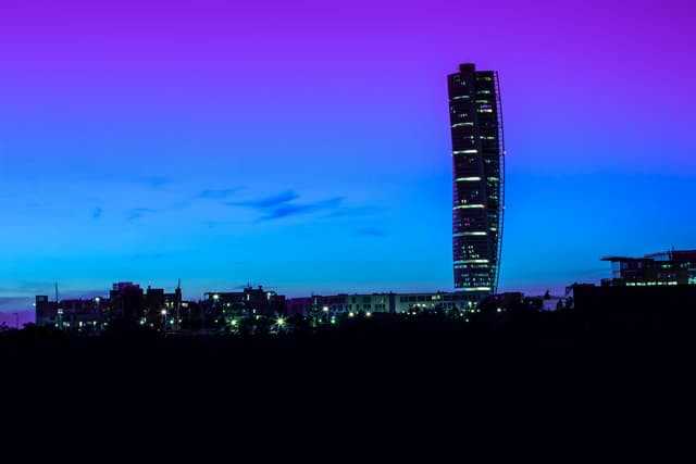 Vibrant night view of the Turning Torso skyscraper in Malmö, Sweden against a colorful sky.