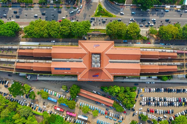 Aerial view of a train station in Jakarta, showcasing urban infrastructure and surrounding greenery.