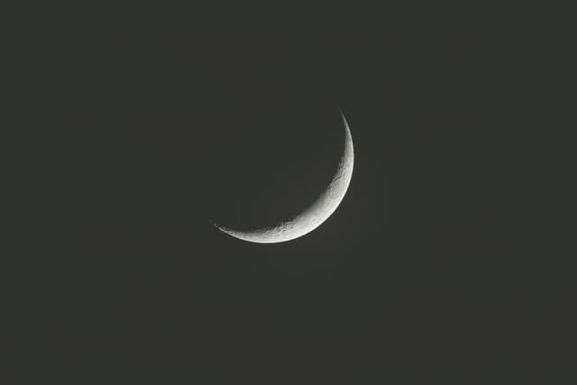 A serene crescent moon floating in the dark night sky, captured in India.