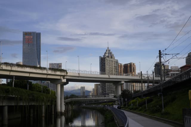 Scenic view of Hong Kong's cityscape with overpass and skyscrapers under a blue sky.