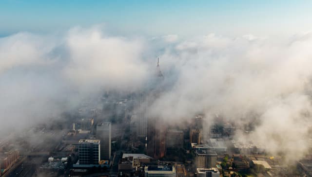A mesmerizing aerial view of Atlanta's skyline enveloped in clouds, showcasing the city's skyscrapers.