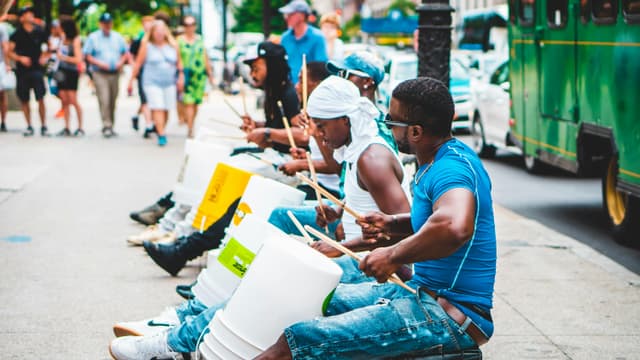 Energetic street performers playing drums in downtown Chicago under summer sun.