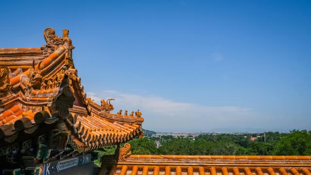 A traditional Chinese roof with intricate details against a clear blue sky in Beijing.
