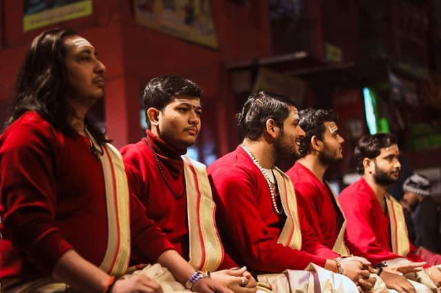 Five men in traditional attire partaking in a Varanasi ritual. Rich cultural ambiance.