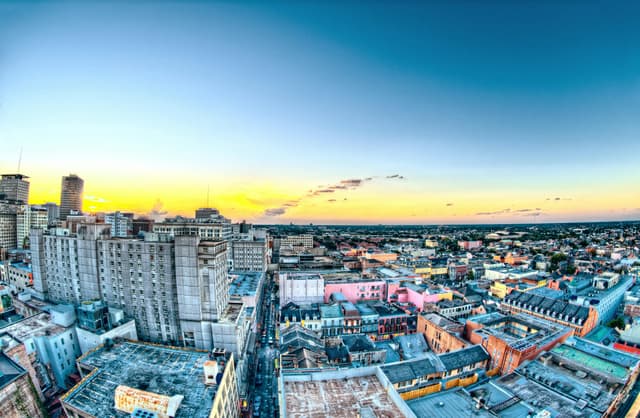 A colorful aerial view of New Orleans cityscape during sunset, showcasing historic buildings and skyline.