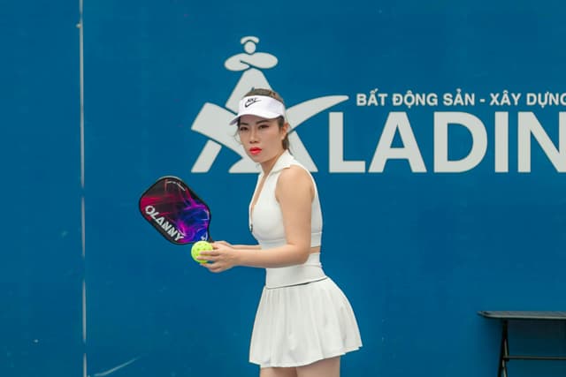Dynamic image of a female pickleball player ready to serve during a match in Hải Phòng, Vietnam.
