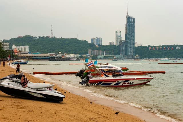 Explore the bustling Pattaya beach in Thailand, showcasing lively speedboats and the iconic cityscape.