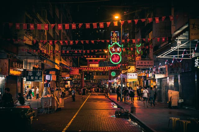 Explore the lively nightlife of Hong Kong with bustling streets illuminated by neon signs and vibrant city life.