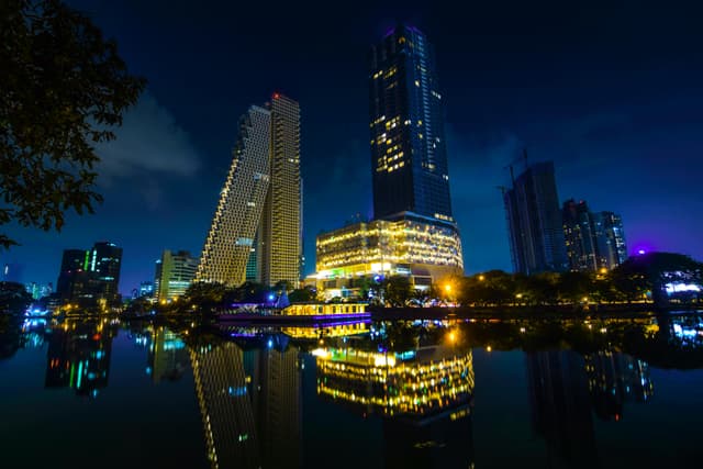 Stunning night view of Colombo's modern skyline reflected in calm waters.