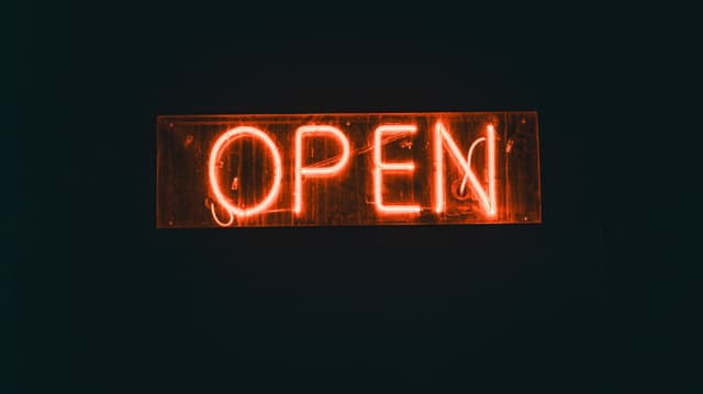 Vibrant neon 'OPEN' sign glowing in a dark urban setting, perfect for nightlife themes.