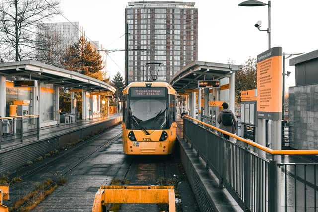 Urban scene showing a yellow tram at sunset in Salford Quays, UK.