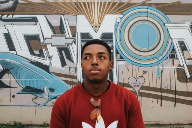 Young man in front of colorful graffiti wall in Richmond, Virginia, reflecting urban vibes.