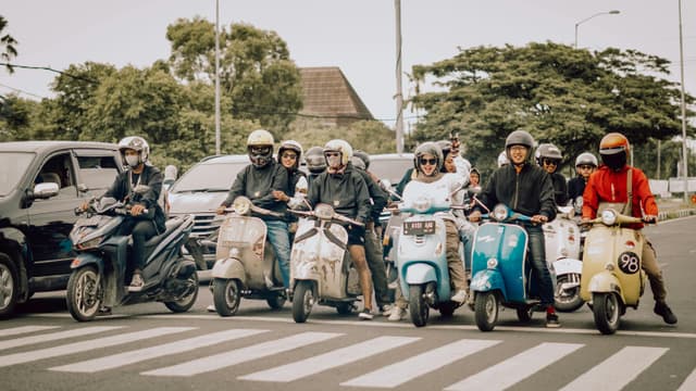 A lively group of scooter riders waiting at a crosswalk in East Java, Indonesia.