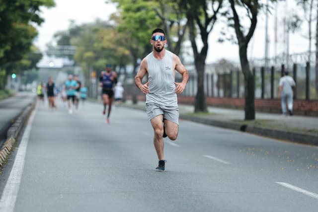Athletic man in a gray outfit running on a city road during a marathon event.