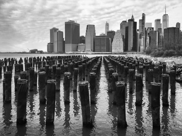 Manhattan skyline and pier pilings in monochrome, seen from Fulton Ferry, Brooklyn, New York, USA, January 2019