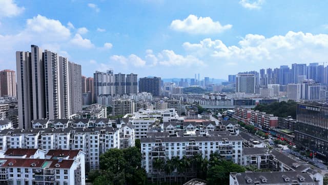 Aerial view of Shenzhen's skyline featuring modern skyscrapers and residential buildings under clear blue skies.