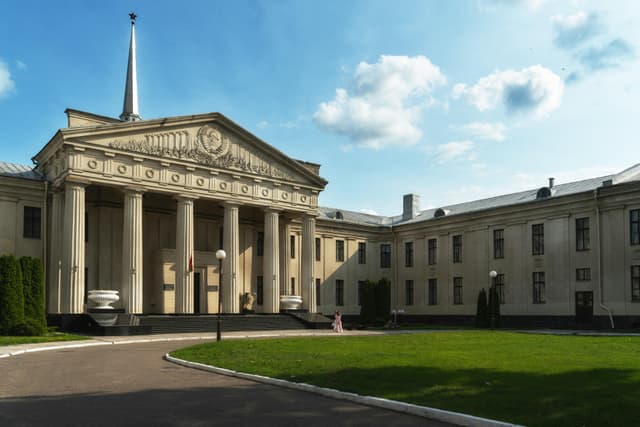 Imposing neoclassical building with columns under a bright blue sky, showcasing architectural grandeur.