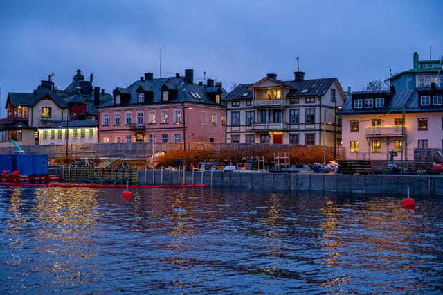 Charming view of waterfront houses reflecting on water at dusk in Stockholm, Sweden.