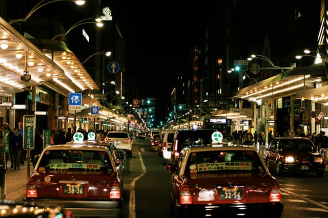 Vibrant night scene in Kyoto featuring busy streets and iconic Japanese taxis.