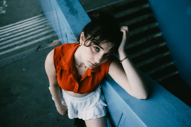 Contemplative young woman on blue stairs, urban setting.