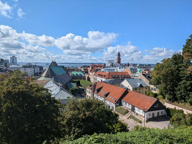 Majestic view of a historic cityscape with red roofs, harbor in the background under a blue sky.
