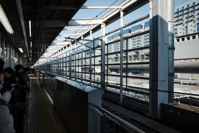 Passengers waiting at a sunny Kyoto train station platform, Japan.